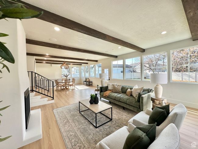 Living area featuring a textured ceiling, beamed ceiling, wood finished floors, recessed lighting, and stairs | Image 16