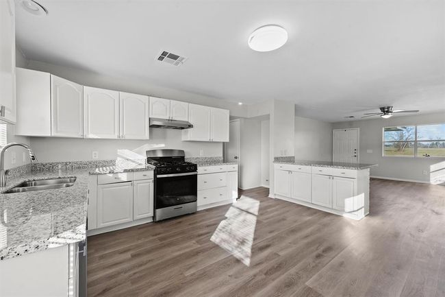 This photo showcases a bright, open-concept kitchen and living area. | Image 8