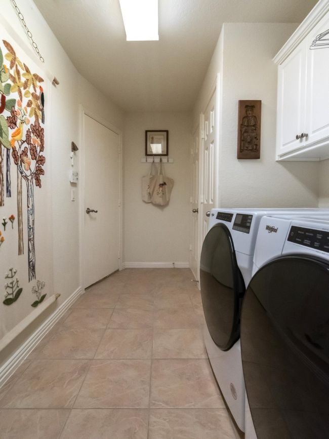 Separate spacious laundry room showcases its built-in cabinets and closet storage. The door on the left is the entry to the attached 2 car garage. | Image 33