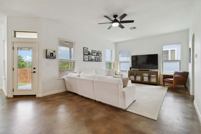 Living room with finished concrete floors, baseboards, and ceiling fan | Image 6
