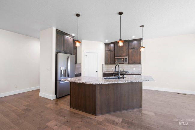 Kitchen with stainless steel appliances, dark brown cabinetry, tasteful backsplash, dark wood-style flooring, and recessed lighting | Image 10