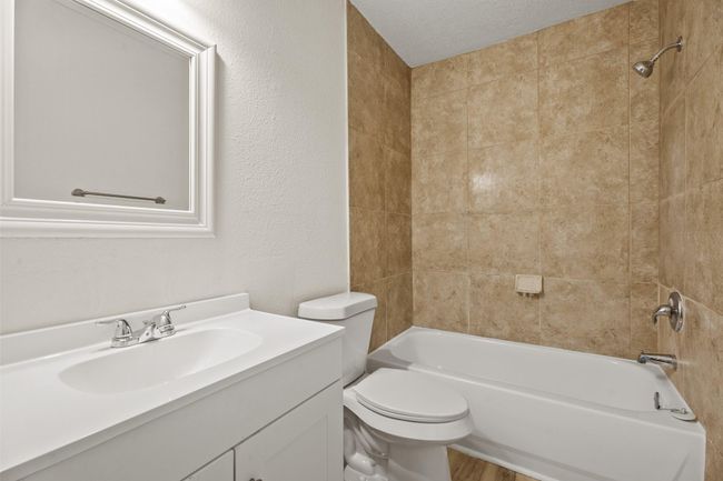 The full hall bath features a brand new vanity, stainless steel fixtures, new white framed mirror, new toilet, and a refinished bathtub with tile surround. | Image 9