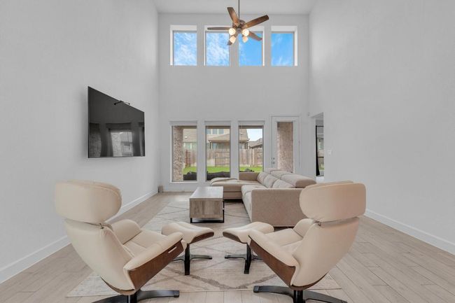 Living room with light wood finished floors and ceiling fan | Image 16