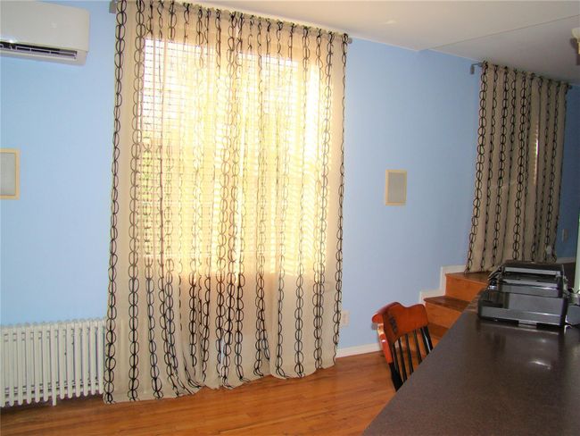 Office area featuring radiator heating unit, hardwood / wood-style floors, and an AC wall unit | Image 8