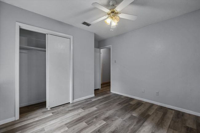 Unfurnished bedroom featuring wood finished floors, a closet, and a ceiling fan | Image 11