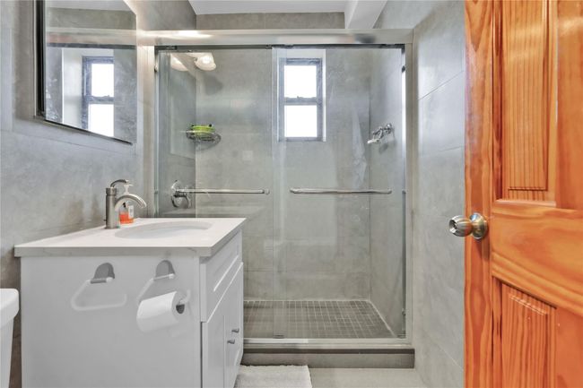 Full bathroom featuring vanity, a stall shower, and tile walls | Image 11