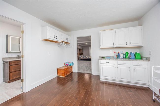 Kitchen with white cabinetry, light stone countertops, dark wood-style flooring, and baseboards | Image 44