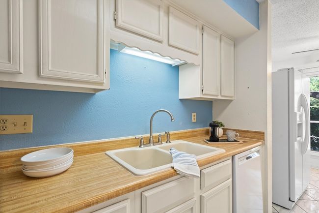 Kitchen with white cabinets, a sink, light countertops, white appliances, and a textured ceiling | Image 14