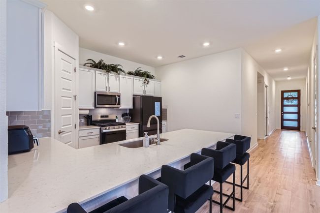 Kitchen with a peninsula, a sink, tasteful backsplash, appliances with stainless steel finishes, and a breakfast bar area | Image 13