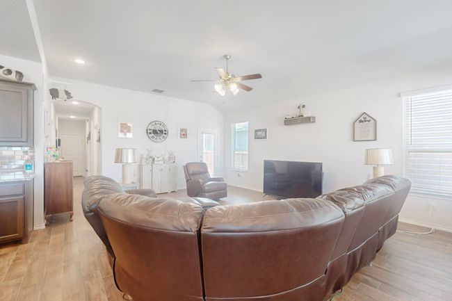 Living area with light wood-style floors, arched walkways, a ceiling fan, visible vents, and baseboards | Image 4
