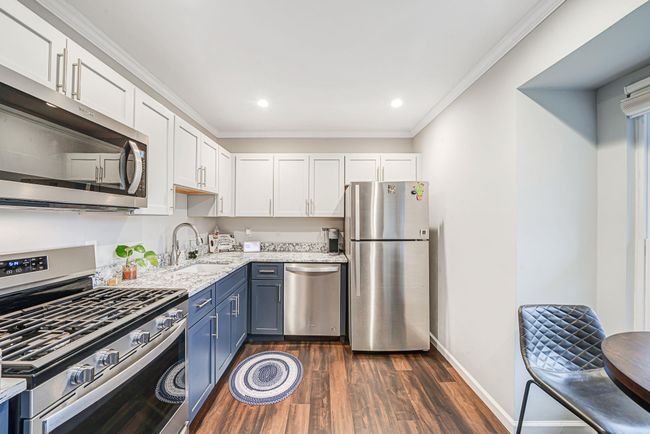 Kitchen with a sink, white cabinetry, dark wood finished floors, stainless steel appliances, and blue cabinetry | Image 14