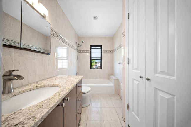 Full bathroom featuring vanity, shower / bathtub combination, toilet, tile walls, and tile patterned flooring | Image 25
