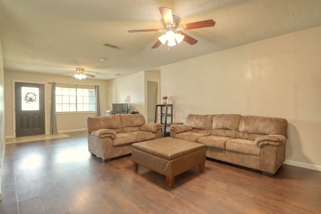 Living area featuring a ceiling fan, a textured ceiling, and dark wood finished floors | Image 8