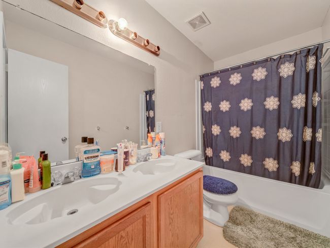 Full bathroom with toilet, double vanity, and shower / bath combination with curtain | Image 25
