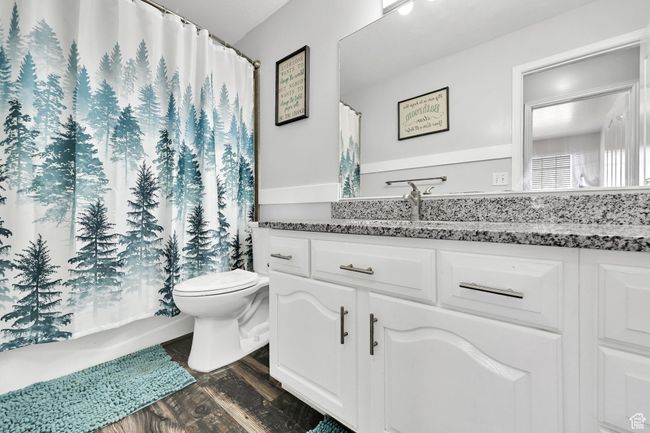 Full bathroom featuring a shower with curtain, wood finished floors, toilet, and vanity | Image 22