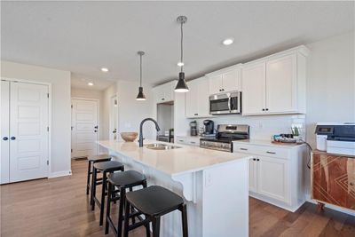 Kitchen with appliances with stainless steel finishes, an island with sink, hardwood / wood-style flooring, and sink | Image 1