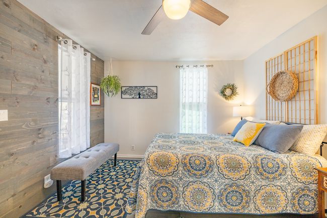 Carpeted bedroom with ceiling fan, wood walls, and baseboards | Image 10