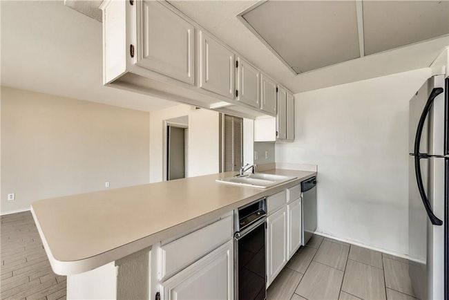 Kitchen featuring a peninsula, appliances with stainless steel finishes, light countertops, and white cabinetry | Image 8