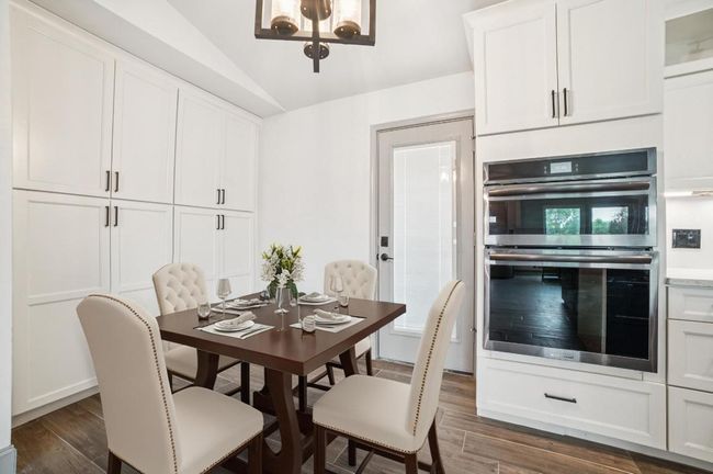 Dining room with dark wood-style floors, a chandelier, and lofted ceiling | Image 12