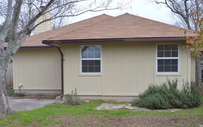 View of side of home featuring a chimney, roof with shingles, and a patio area | Image 10