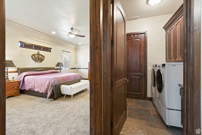 Laundry room with cabinet space, independent washer and dryer, ceiling fan, and dark stone finish flooring | Image 30