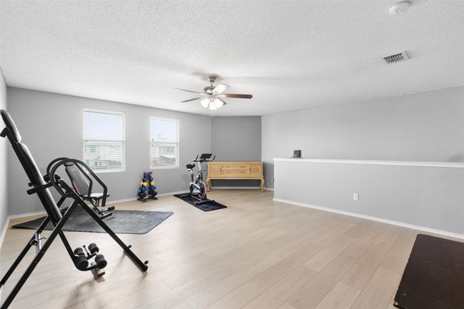 Workout room with a textured ceiling, a ceiling fan, and light wood finished floors | Image 18