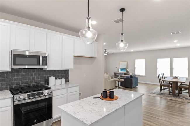 Kitchen featuring white cabinetry, appliances with stainless steel finishes, a center island, visible vents, and decorative backsplash | Image 19