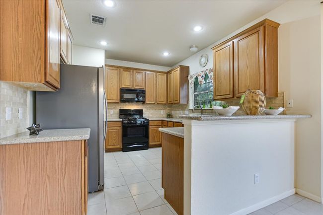 Kitchen with black appliances, backsplash, a peninsula, and recessed lighting | Image 7