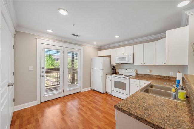 Kitchen featuring white appliances, ornamental molding, a sink, baseboards, and visible vents | Image 6