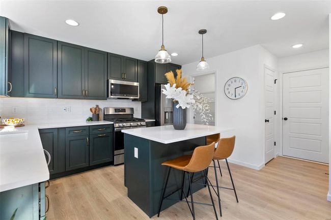 Kitchen with appliances with stainless steel finishes, hanging light fixtures, light hardwood / wood-style floors, and decorative backsplash | Image 9