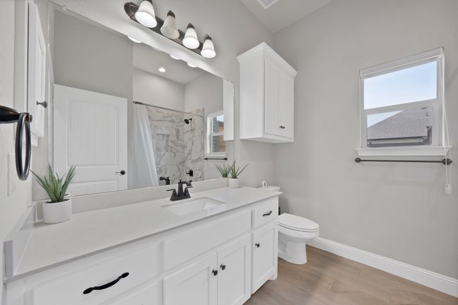 Full bath with toilet, vanity, curtained shower, wood finished floors, and baseboards | Image 20