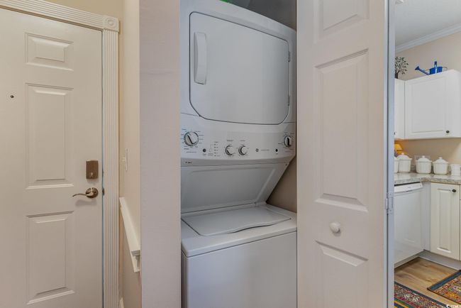 Laundry area with crown molding, stacked washer and dryer, and light hardwood / wood-style floors | Image 9