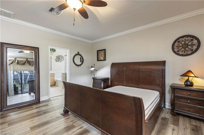 Bedroom featuring visible vents, ensuite bath, crown molding, and wood finished floors | Image 17