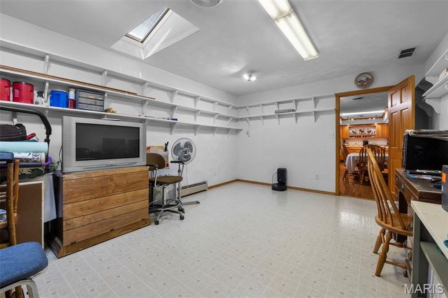 Home office featuring light flooring, a skylight, and baseboard heating | Image 82
