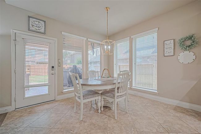 This spacious eating nook boasts floor-to-ceiling windows that invite the outdoors in, offering backyard views and a naturally bright atmosphere. | Image 16