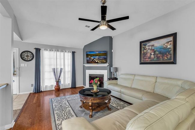 Amazing living room with a beautiful fireplace and a large window, wood flooring and ceiling fan. | Image 11