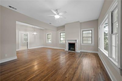 Unfurnished living room featuring dark wood-type flooring and ceiling fan with notable chandelier | Image 3