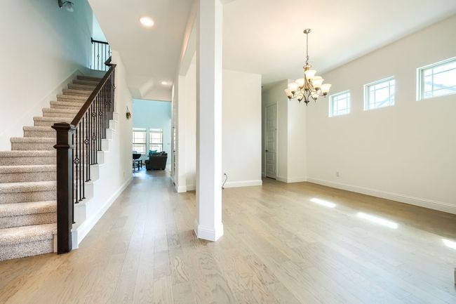 Unfurnished dining area with baseboards, an inviting chandelier, light wood-style floors, and stairs | Image 4