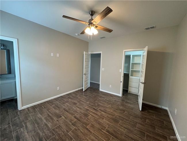 Unfurnished bedroom with dark wood-style floors, baseboards, and a walk in closet | Image 16