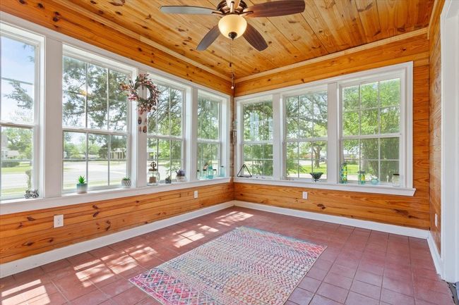 Unfurnished sunroom with wooden walls, baseboards, tile patterned flooring, and wooden ceiling | Image 14