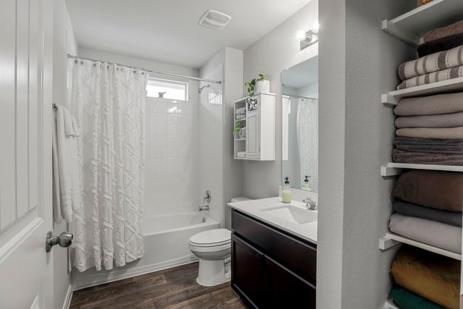 Full bath featuring wood finished floors, shower / tub combo with curtain, and vanity | Image 19