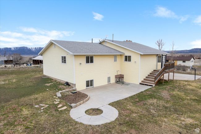 Rear view of property with a yard, a shingled roof, a mountain view, and a patio area | Image 32