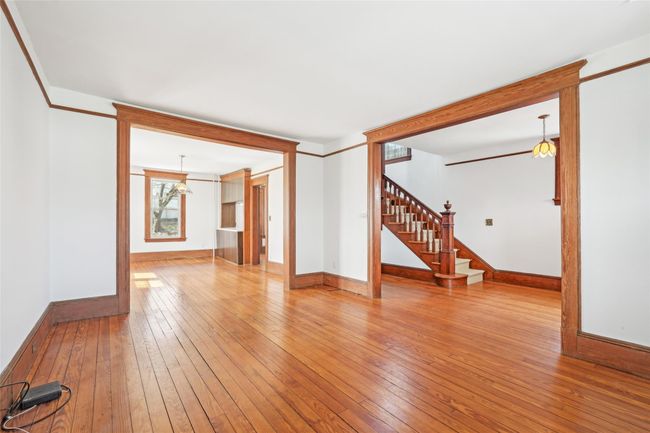 Unfurnished living room featuring crown molding, stairs, baseboards, and hardwood / wood-style flooring | Image 6