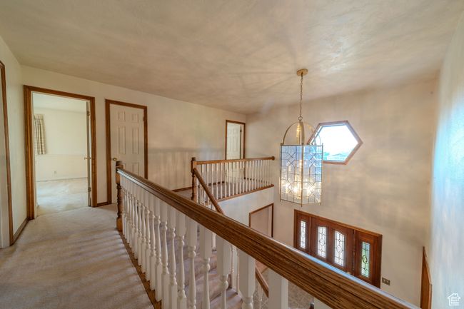 Corridor featuring light colored carpet, an inviting chandelier, and an upstairs landing | Image 18