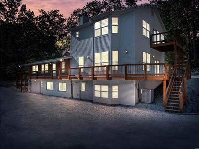 Back house at dusk featuring a wraparound deck and new in 2024 central AC/heat pump unit | Image 1