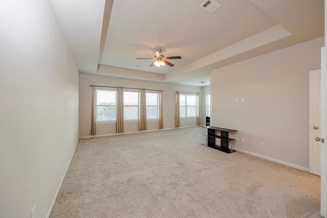 Unfurnished living room with a raised ceiling, a ceiling fan, healthy amount of natural light, and carpet floors | Image 34