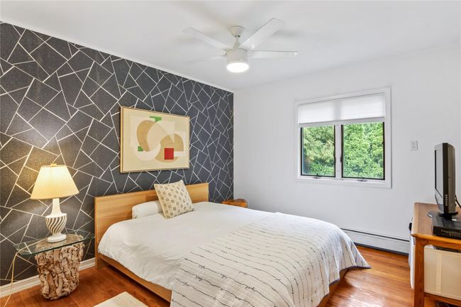 Bedroom with an accent wall, a baseboard heating unit, wood finished floors, and ceiling fan | Image 20