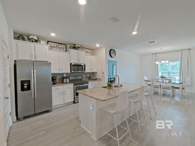 Kitchen featuring white cabinets, appliances with stainless steel finishes, and an island with sink | Image 2