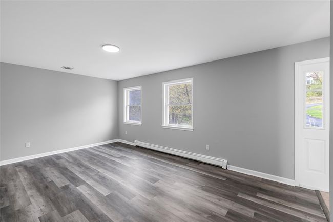 Spare room featuring dark wood-type flooring, a wealth of natural light, visible vents, and baseboard heating | Image 25