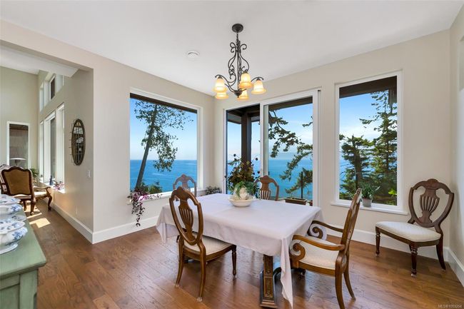 Dining area with dark wood-style flooring, a water view, and a chandelier | Image 32